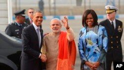 U.S. President Barack Obama shakes hand with Indian Prime Minister Narendra Modi, as first lady Michelle Obama stand beside them, upon arrival at the Palam Air Force Station in New Delhi, India, Sunday, Jan. 25, 2015. Obama's arrival Sunday morning in the bustling capital of New Delhi marked the first time an American leader has visited India twice during his presidency. Obama is also the first to be invited to attend India's Republic Day festivities, which commence Monday and mark the anniversary of the enactment of the country's democratic constitution. (AP Photo)