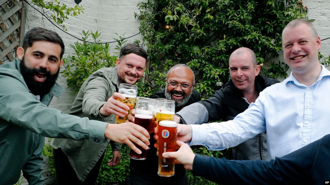 Men enjoy their first beers as the Chandos Arms pub reopens, in London, July 4, 2020. 