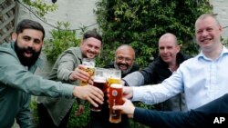 Men enjoy their first beers as the Chandos Arms pub reopens, in London, July 4, 2020. 