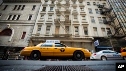 Sebuah taksi kuning khas New York melintasi jalanan di depan gedung di 51 Park Place, di lokasi ditemukannya bagian reruntuhan pesawat yang diyakini digunakan dalam serangan 11 September (26/4). 