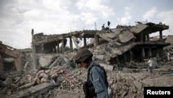 FILE - An Afghan policeman walks at the site a truck bomb blast in Kabul, Aug. 7, 2015. A U.S. Green Beret admitted killing a man in Afghanistan he suspected was a bombmaker. There is enough evidence to charge him with murder.