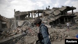 FILE - An Afghan policeman walks at the site a truck bomb blast in Kabul, Aug. 7, 2015. A U.S. Green Beret admitted killing a man in Afghanistan he suspected was a bombmaker. There is enough evidence to charge him with murder.