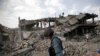 FILE - An Afghan policeman walks at the site a truck bomb blast in Kabul, Aug. 7, 2015. 