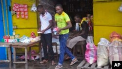 A man, center, walks out of a re-opened store after he shopped for daily goods near West Point slum in Monrovia, Liberia, Aug. 30, 2014. 