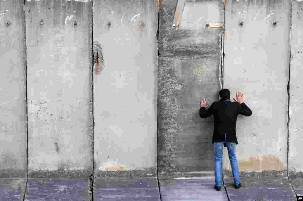 A man looks through a space during the art performance "Wall watching — climb the wall together" of the National Theatre Weimar, ahead of the 30th anniversary of the fall of the Berlin Wall, in Weimar, Germany.