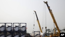 Workers prepare to lift a giant blade to be used as part of wind turbines at the Vestas Wind Technology (China) Co. Ltd. factory in Tianjin, China, September 14, 2010.