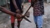 Integrantes de un grupo de vigilantes del vecindario sostienen un martillo y machetes mientras posan para una fotografía después de que el presunto líder de una pandilla, Makandal, fuera asesinado e incendiado, en Puerto Príncipe, Haití, el 20 de marzo de 2024.
