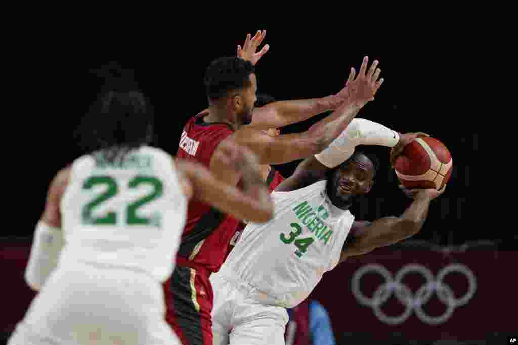 Nigeria&#39;s Ike Nwamu (34), right, is blocked by Germany&#39;s Johannes Thiemann (32), center, during men&#39;s basketball preliminary round game at the 2020 Summer Olympics, Wednesday, July 28, 2021, in Saitama, Japan. (AP Photo/Eric Gay)