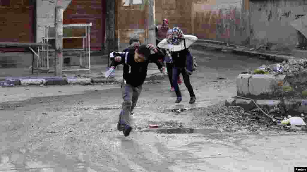 Children run across a street to avoid snipers in Deir al-Zor, eastern Syria Feb. 16, 2014. 