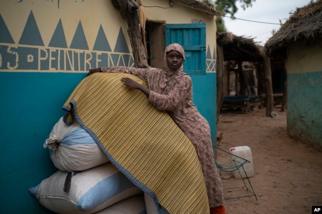 FILE - Mariama Konte, 20, stands inside her home in a village near Goudiry, Senegal, Nov. 26, 2018. Konte, who married Abdrahamane when she was 12 and he was 21, is living the consequences of the family's decision in November to mourn him after nearly four years of waiting.
