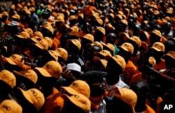 Supporters of Kenyan opposition leader Raila Odinga stand in the sun wearing baseball caps in his party's orange color and bearing his initials, as they await his arrival at a rally in Uhuru Park in Nairobi, Kenya, Oct. 25, 2017.