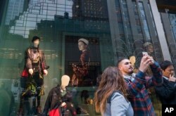 People take photos across Fifth Avenue of Trump Tower (reflected in window) in New York, Nov. 9, 2016. Donald Trump claimed his place Wednesday as America's 45th president, an astonishing victory for the celebrity businessman and political novice who capitalized on voters' economic anxieties, took advantage of racial tensions and overcame a string of sexual assault allegations on his way to the White House.