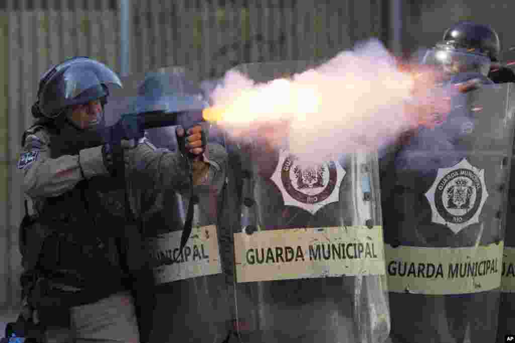 Seorang anggota pasukan anti huru-hara menembakkan gas air mata ke arah demonstran di Rio de Janeiro, Brazil.