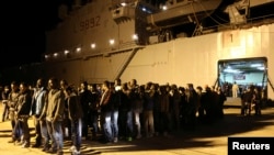 Migrants stand in line at the Sicilian harbour of Augusta, April 9, 2014. 