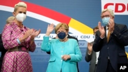 German Chancellor Angela Merkel waves as leading CDU members applaud after the parliament elections at the Christian Democratic Union, CDU, party's headquarters in Berlin, Sept. 26, 2021