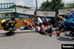 People take cover behind barriers as shots are fired near the Simon Bolivar international bridge, on the border between Colombia and Venezuela, in Cucuta, Colombia, May 3, 2019.