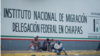 Migrantes sentados frente al Instituto Nacional de Migración en Chiapas, México.