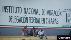 Migrantes sentados frente al Instituto Nacional de Migración en Chiapas, México.