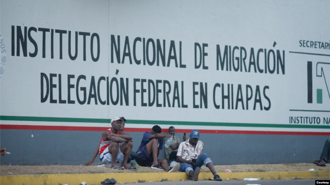 Migrantes sentados frente al Instituto Nacional de Migración en Chiapas, México.