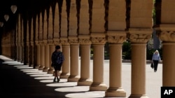 In this April 9, 2019 photo, pedestrians walk on the campus at Stanford University in Stanford, Calif. (AP Photo/Jeff Chiu)