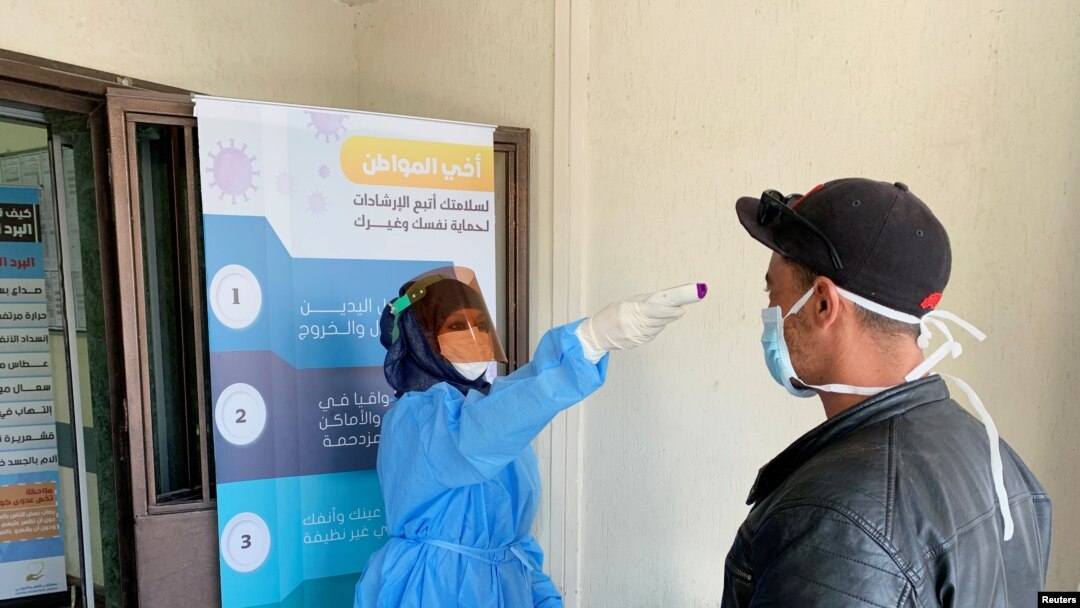A nurse checks the temperature of a man before he enters a medical clinic, following the outbreak of the coronavirus disease (COVID-19), in Misrata, Libya March 31, 2020.