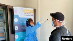 A nurse checks the temperature of a man before he enters a medical clinic, following the outbreak of the coronavirus disease (COVID-19), in Misrata, Libya March 31, 2020.