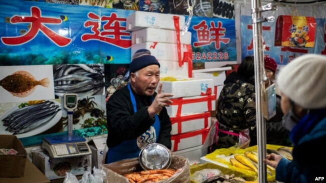 资料照:北京一家海鲜市场的小贩正在向顾客兜售水产品。(2020年1月15日)