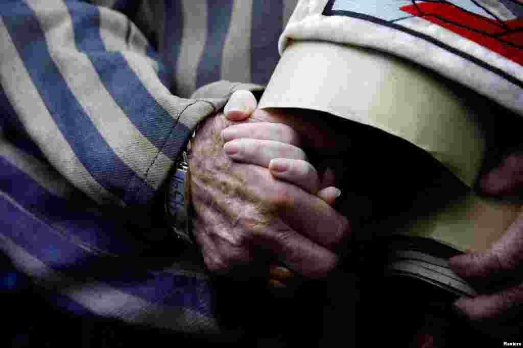 폴란드 오시비엥침에 있는 전 아우슈비츠&nbsp;강제 수용소에서 &#39;산 자들의&nbsp;행진&#39;이 열린 가운데 노인이 된 홀로코스트 생존자가 손녀의 손을 잡고 있다.