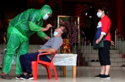 Seorang petugas kesehatan melakukan tes usap COVID-19 kepada seorang pengunjung di sebuah kelenteng di Tangerang, Sabtu, 6 Februari 2021. (Foto: Tatan Syuflana/AP)