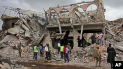 Somali security forces and others gather and search for bodies near destroyed buildings at the scene of Saturday's blast, in Mogadishu, Somalia, Oct. 15, 2017.