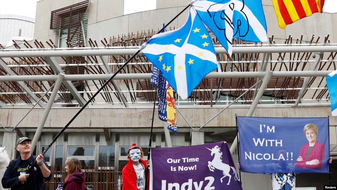 FILE - People hold Saltires and pro-independence flags outside Scotland's Parliament in Holyrood, Edinburgh, Britain, March 28, 2017.