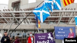 FILE - People hold Saltires and pro-independence flags outside Scotland's Parliament in Holyrood, Edinburgh, Britain, March 28, 2017.