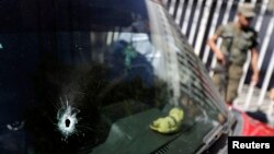 A car windshield with a bullet hole is seen at a crime scene outside the San Juan De Dios Hospital, Guatemala City, March 10, 2015. 