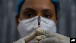 A health worker checks a syringe before performing a trial run of a COVID-19 vaccine delivery system, as India prepares to kick off the coronavirus vaccination drive, in Gauhati, India, Jan. 8, 2021. 