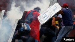 Estudiantes se protegen de los gases lacrimógenos lanzados por la Guardia Nacional al finalizar las protestas del domingo, en Caracas .