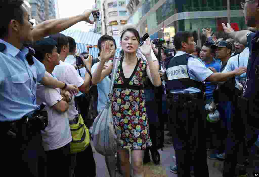 A pro-democracy activist raises her hands to indicate her agreement to leave their protest area as local police hold back residents and pro-Beijing supporters in Kowloon's crowded Mong Kok district, Hong Kong, Oct. 3, 2014.