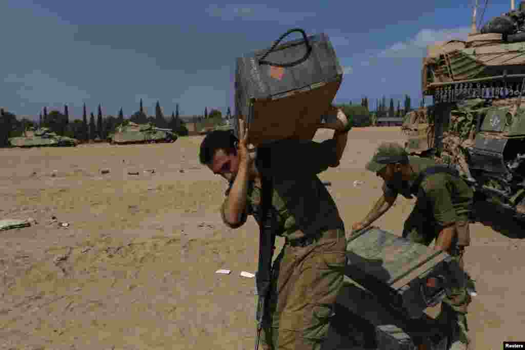 Israeli soldiers carry cases at a staging area near the border with the Gaza Strip July 31, 2014