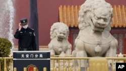 资料照：一名中国警察站在北京天安门前的石狮子旁。（2021年3月11日）
