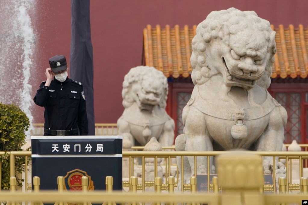 一名警察站在北京天安门城楼旁的石狮子边执勤。（2021年3月11日）(photo:VOA)
