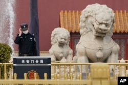 一名警察站在北京天安门城楼旁的石狮子边执勤。（2021年3月11日）
