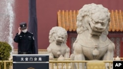 中國警察守衛在北京天安門前的石獅子旁。 （2021年3月11日）