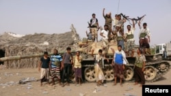 FILE - Tribal fighters loyal to the Yemeni government stand by a tank in al-Faza area near Hodeida, Yemen, June 1, 2018.