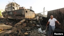 Workers inspect damage at the site of an air strike on the maintenance hub at the Hodeida port, Yemen, May 27, 2018. 