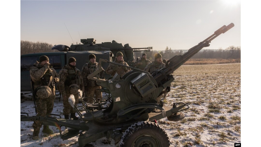 Prajurit Ukraina dari tim pemburu drone berdiri di samping autocannon anti-pesawat laras ganda yang mereka gunakan untuk menargetkan drone yang diluncurkan Rusia, di pinggiran Kyiv, 30 November 2023. (Foto: AFP)