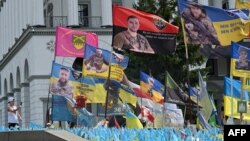 Un niño toma una fotografía de un monumento improvisado para los soldados ucranianos caídos en la Plaza de la Independencia en Kiev, el 26 de julio de 2024, en medio de la invasión rusa en Ucrania. [Foto de Sergei SUPINSKY / AFP]