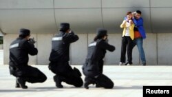 Police officers take aim with their weapons at a man playing the role of an attacker as he holds a woman hostage during an anti-terrorism drill at a railway station in Zhengzhou, China, May 7, 2014.