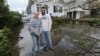 Kathy and Jeffrey Frey pose for a photograph outside their home on 7th Street which is flooded from the effects of Hurricane Sandy on Oct., 30, 2012, in Bayville, N.Y.