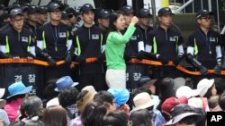 An Evangelical Baptist Church believer shouts slogans against the government as police officers stand guard in font of believers sitting by the main gate of the church in Anseong, South Korea, June 11, 2014. 