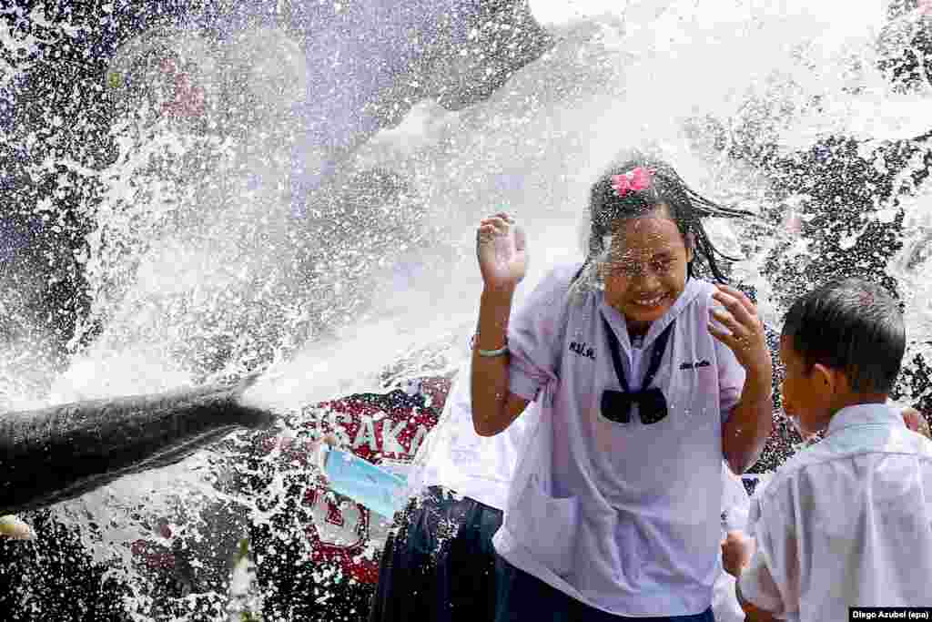 A schoolgirl is soaked with water thrown by an elephant during the Songkran Festival celebration, also known as the water festival in the ancient world heritage city of Ayutthaya, Thailand.