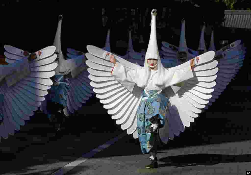 Heron-hooded dancers perform as they parade down the streets toward Sensoji Temple in Tokyo, Japan.